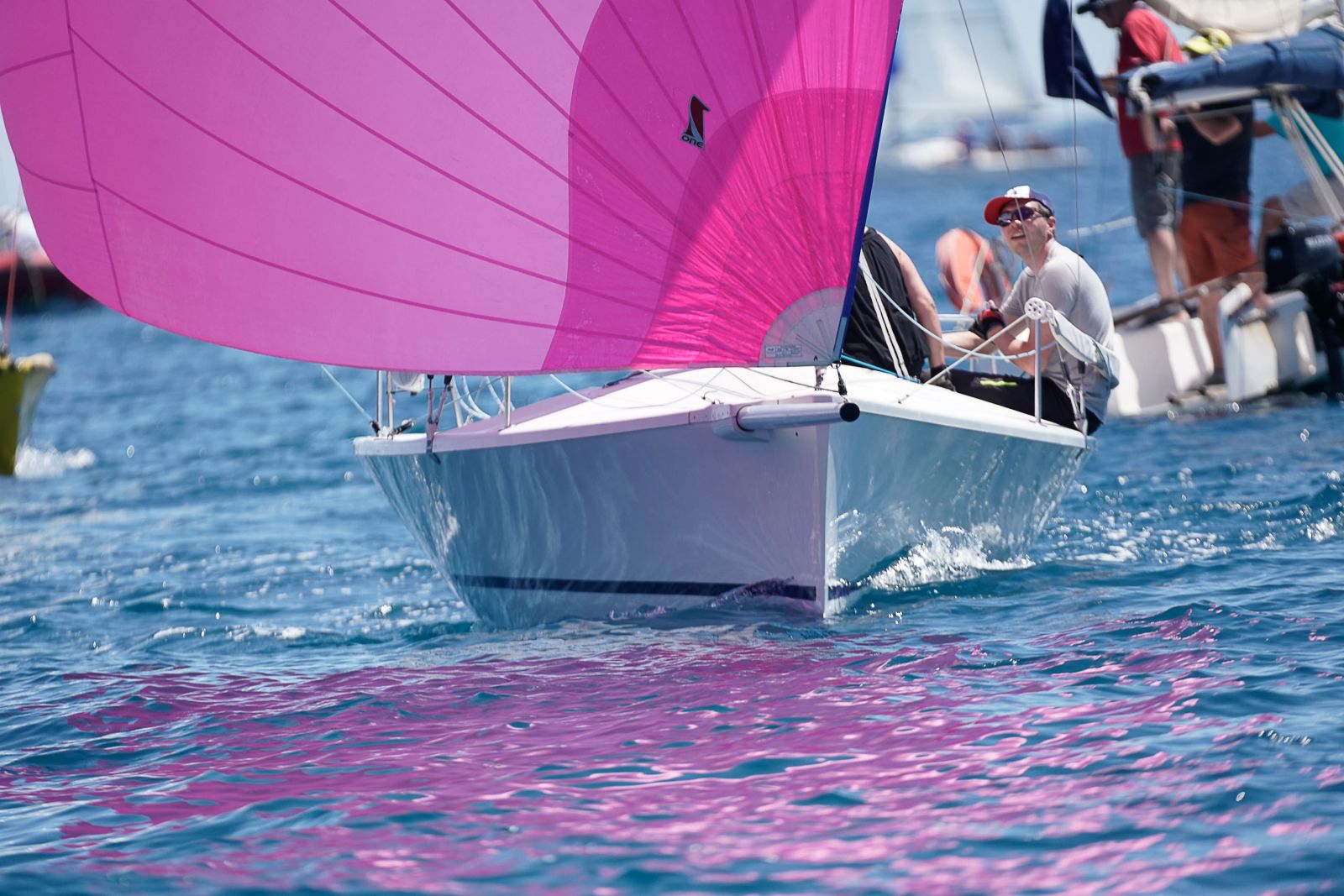 Spinnaker rose et équipage au travail sur la plage avant